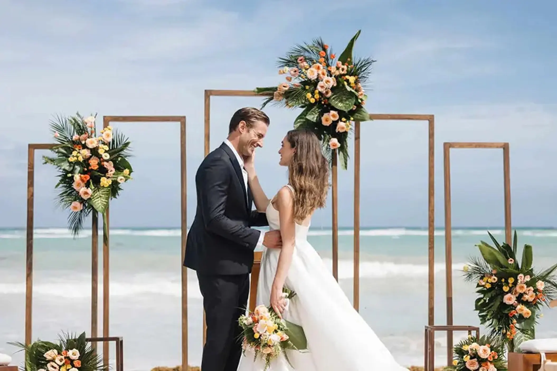 Bride and groom standing before a beach ceremony arch at UNICO 20°87°, Riviera Maya