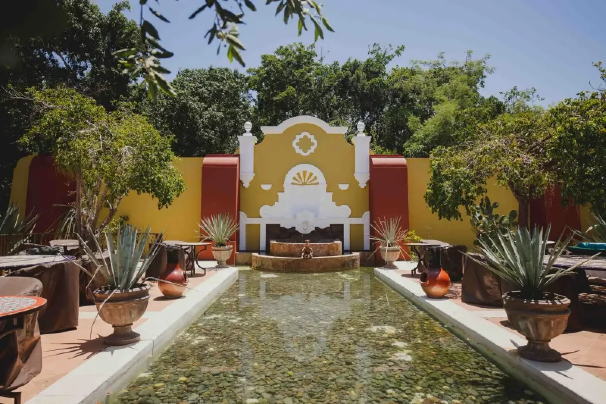 Outdoor hacienda terrace with a reflection pool and fountain at Valentin Imperial, Riviera Maya