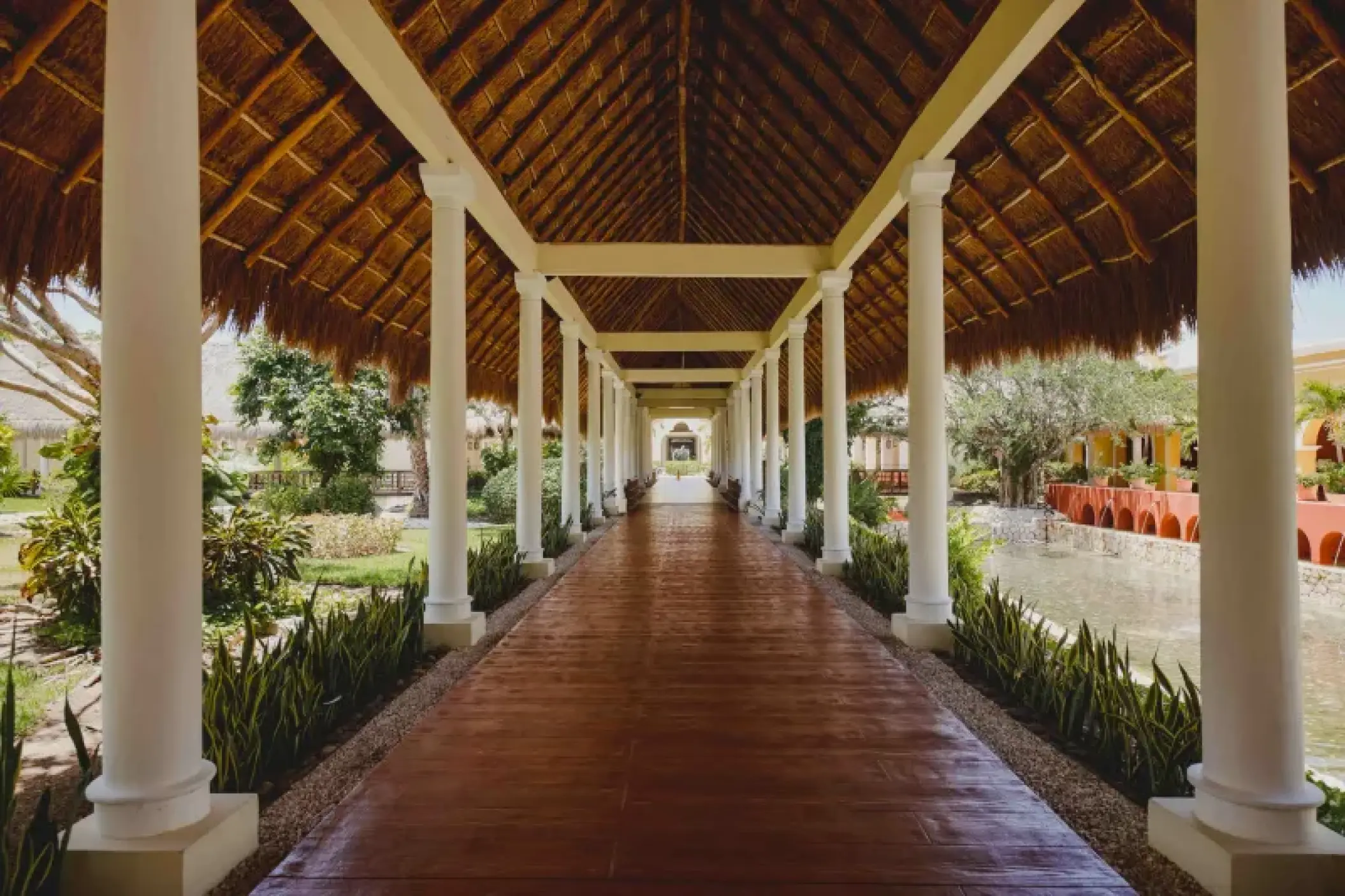 Thatched roof walkway with white columns at Valentin Imperial, Riviera Maya
