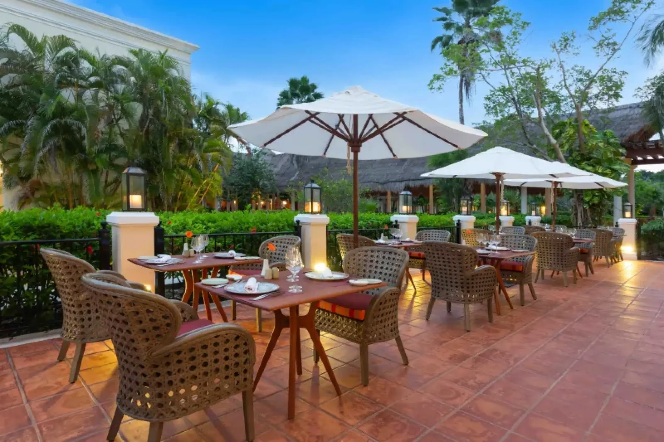 Outdoor terrace dining with white umbrellas and wicker chairs at Valentin Imperial, Riviera Maya