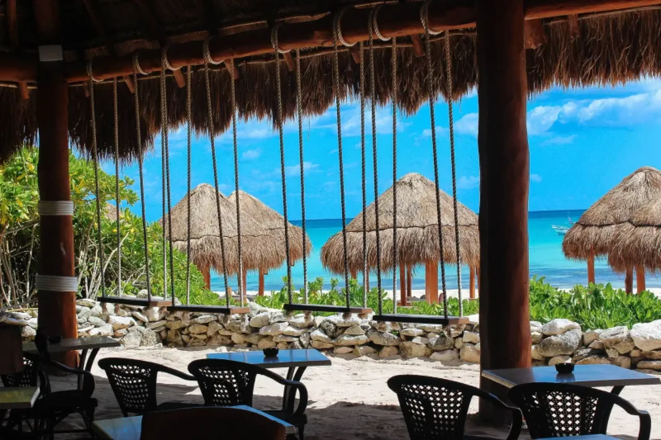 Sunrise beach bar with swing seating and palapas at Valentin Imperial, Riviera Maya