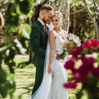 The couple posing in a garden for their Mayan wedding at Valentin Imperial, Riviera Maya