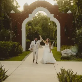 The couple celebrating their entrance under an archway at Valentin Imperial, Riviera Maya