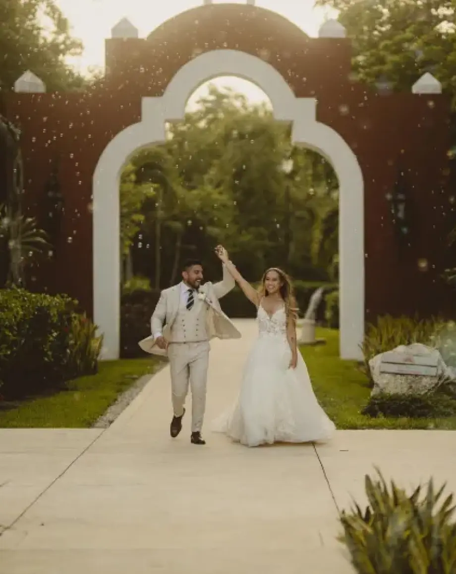 The couple celebrating their entrance under an archway at Valentin Imperial, Riviera Maya