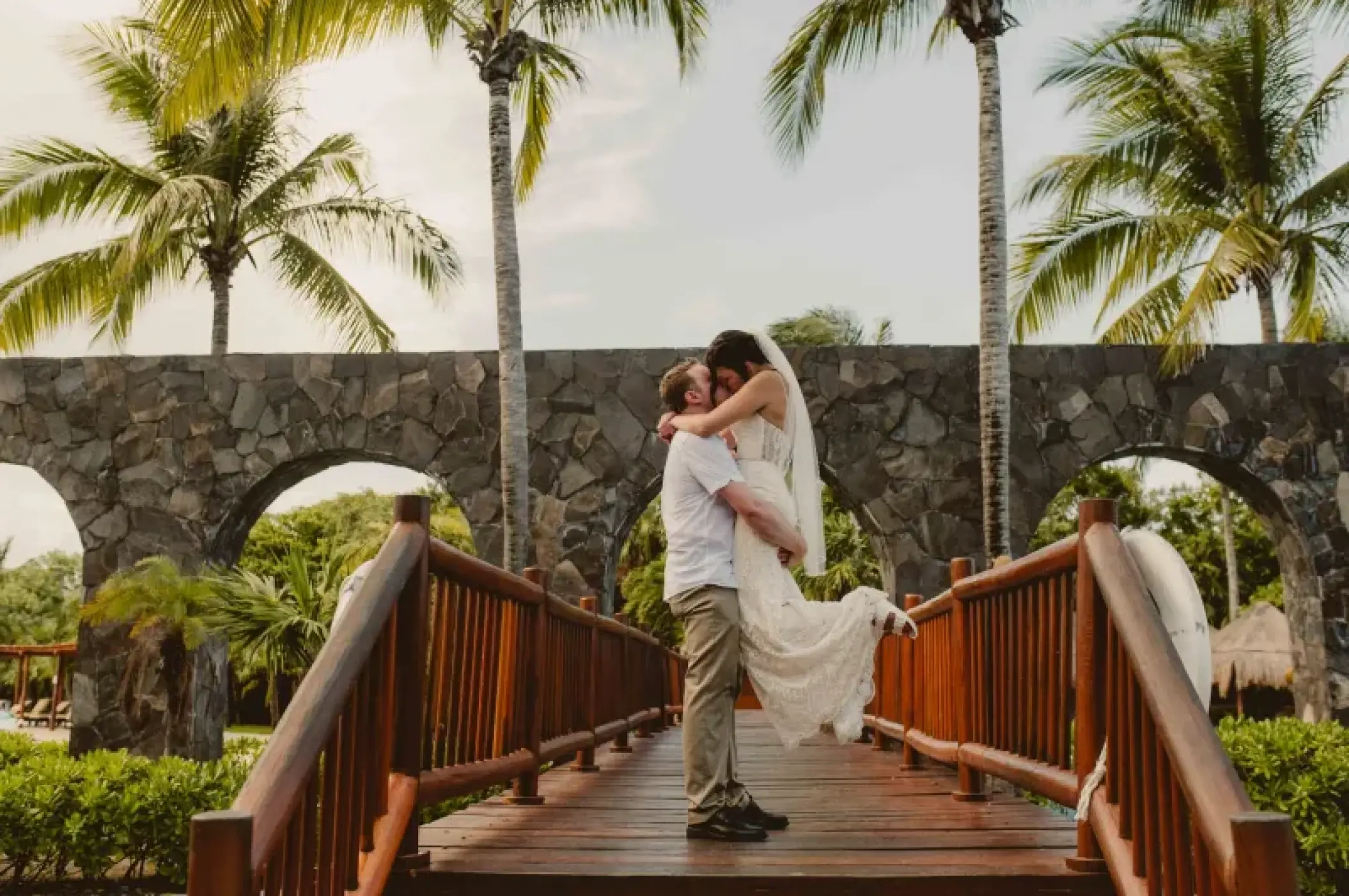 Groom lifting the bride on a wooden bridge at Valentin Imperial, Riviera Maya