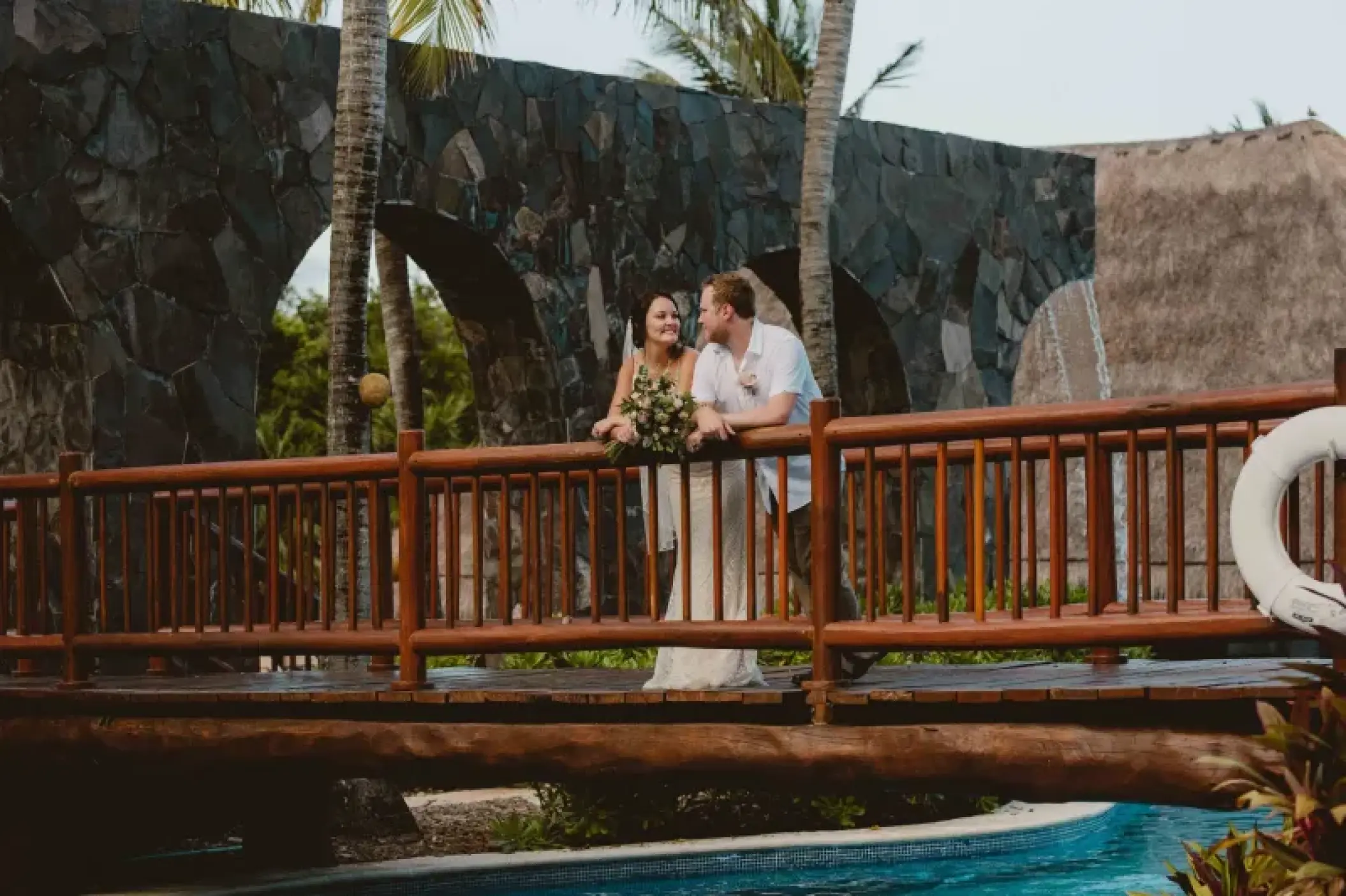 The bride and groom standing on a wooden bridge at Valentin Imperial Riviera Maya