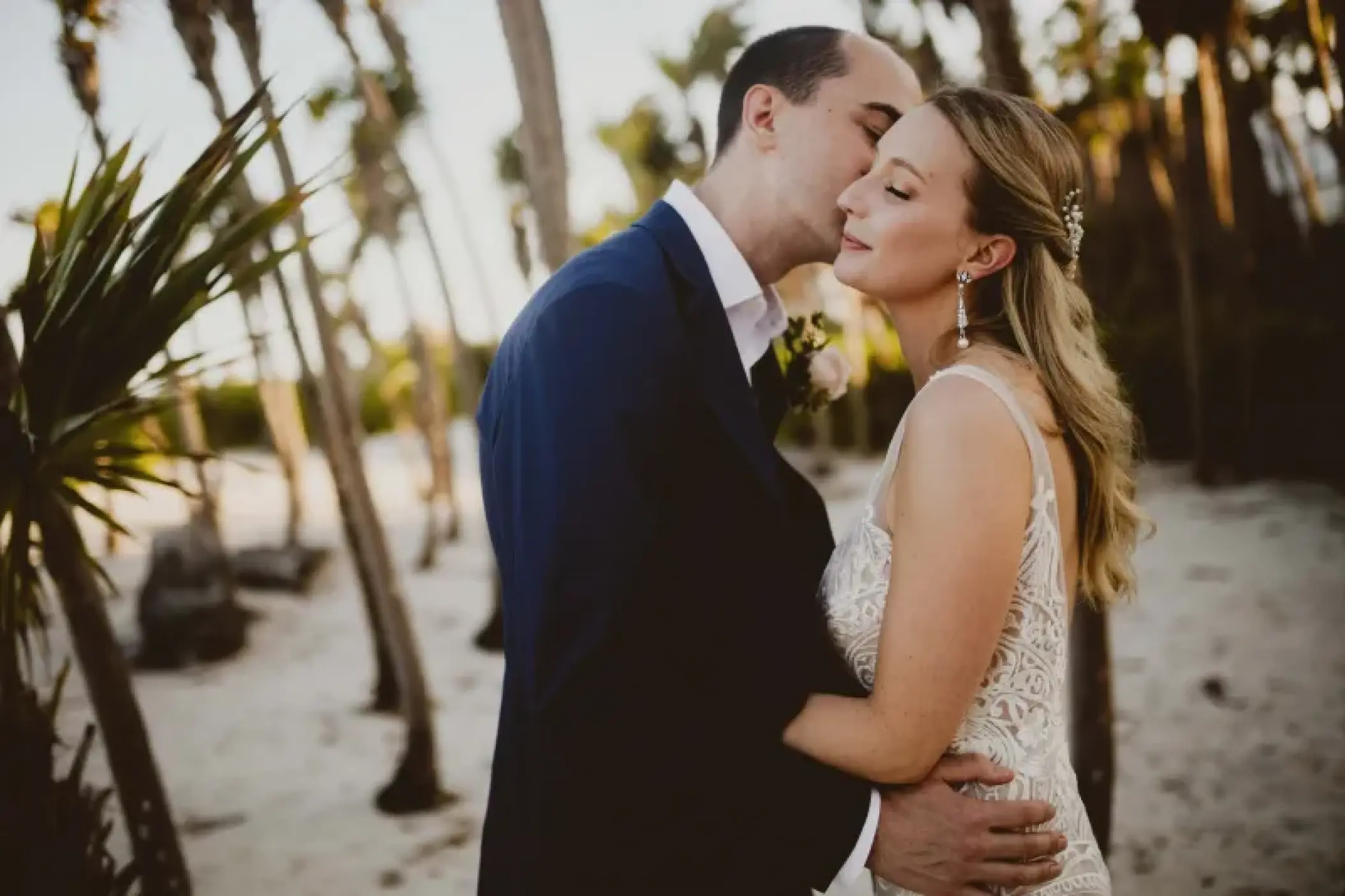 Groom kissing the bride's forehead during a wedding portrait at Valentin Imperial, Riviera Maya