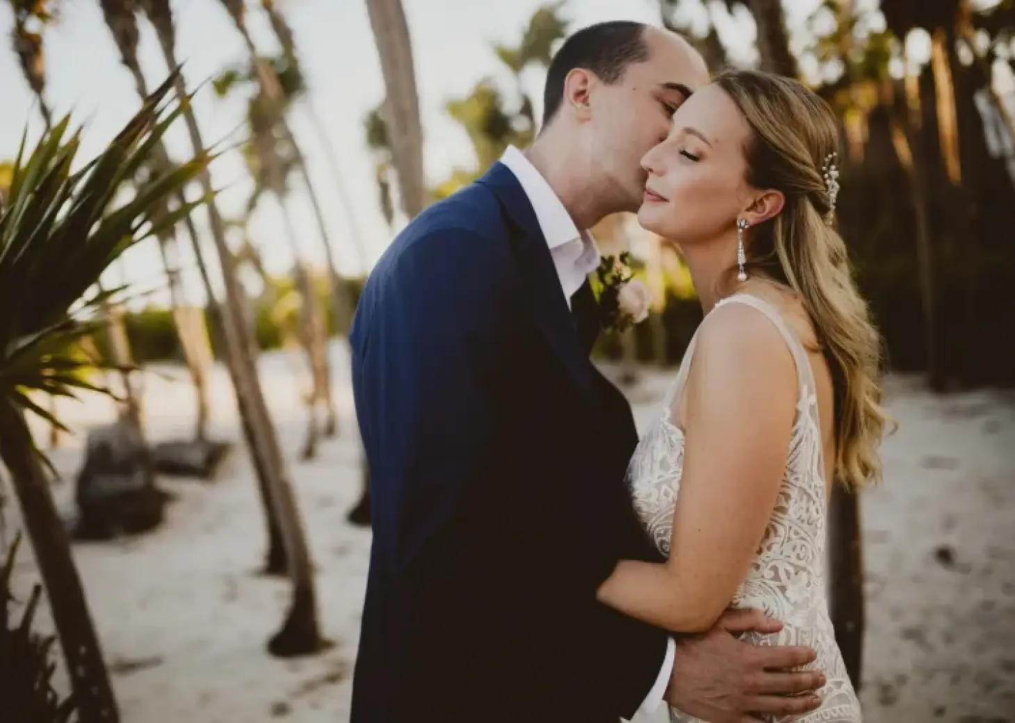 Groom kissing the bride's forehead during a wedding portrait at Valentin Imperial, Riviera Maya