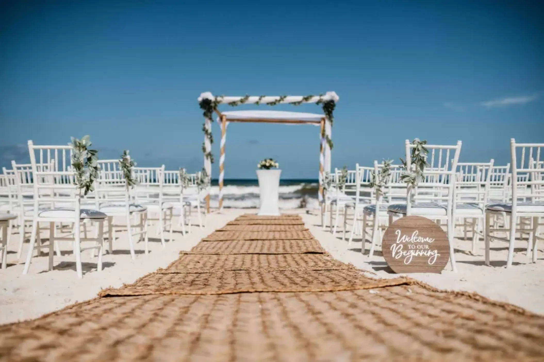 Beachfront wedding ceremony with a jute aisle runner and wooden huppah at Valentin Imperial, Riviera Maya