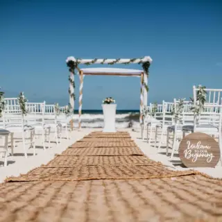 Beachfront wedding ceremony with a jute aisle runner and wooden huppah at Valentin Imperial, Riviera Maya