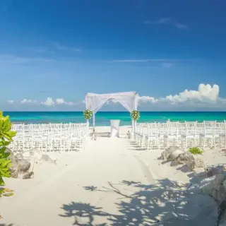 Beachfront wedding ceremony with white huppah and chairs at Valentin Imperial, Riviera Maya