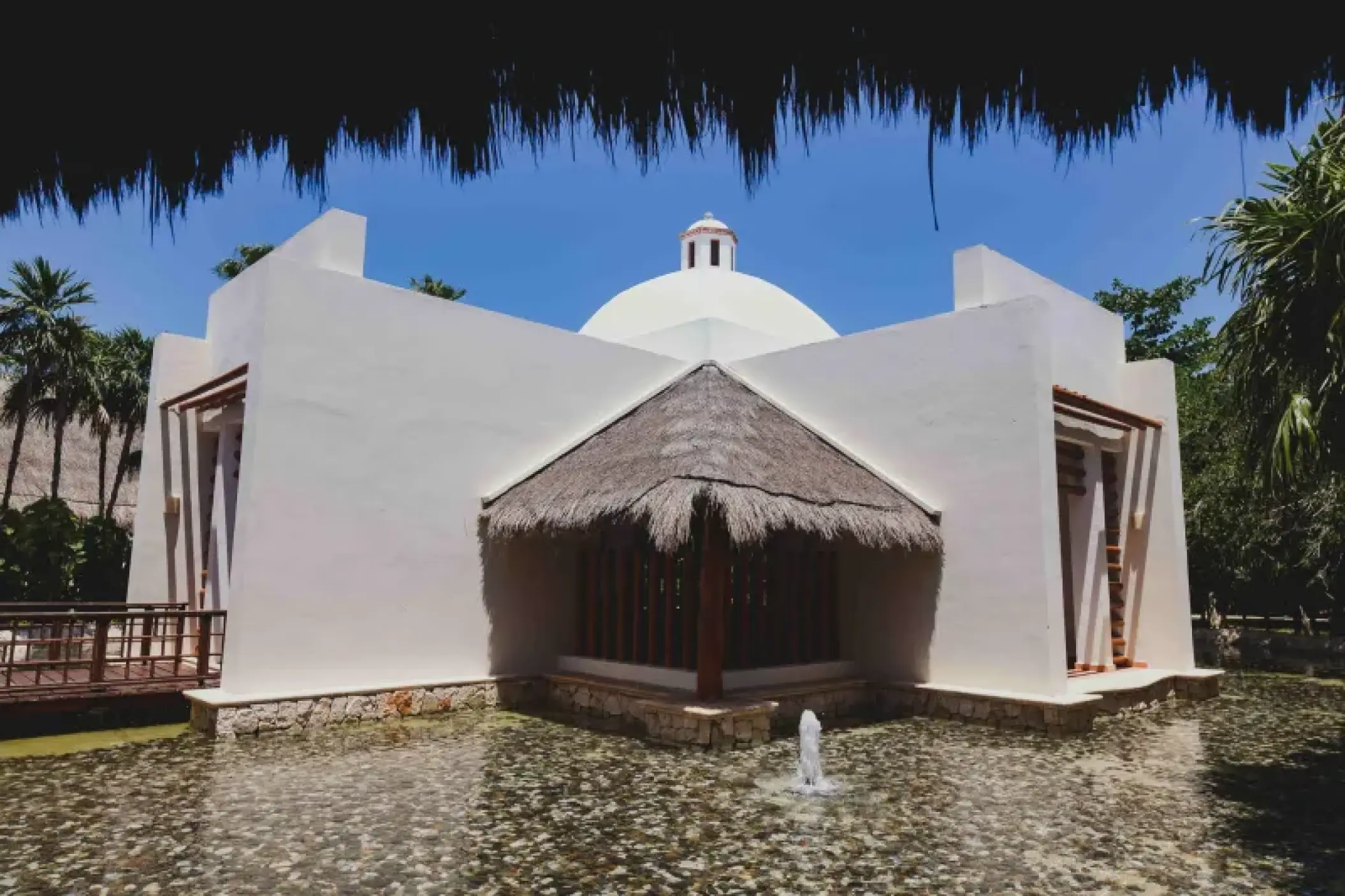 White wedding chapel with a palapa entrance at Valentin Imperial, Riviera Maya