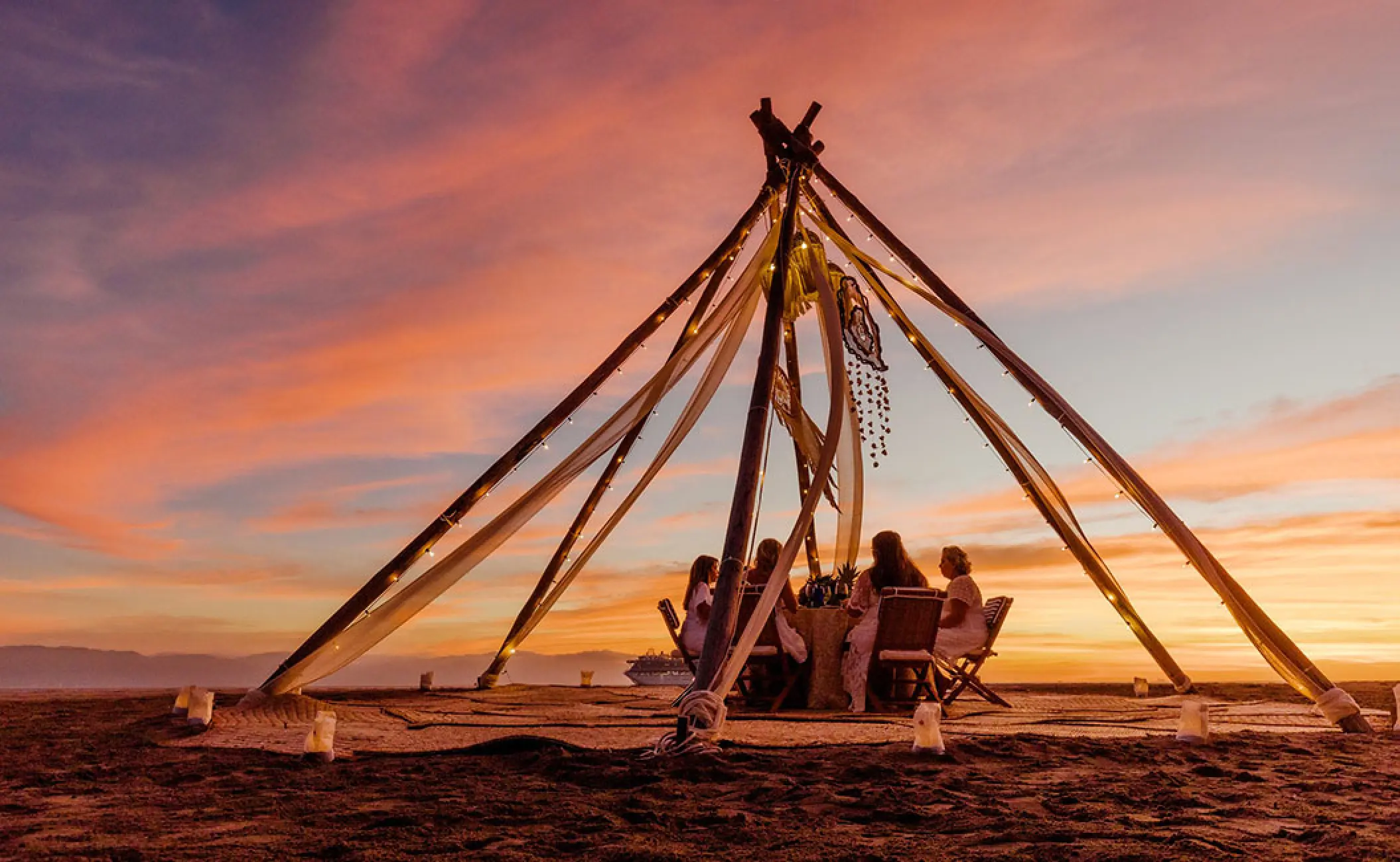 Family dinner under a lit tipi structure at sunset at Velas Vallarta, Puerto Vallarta
