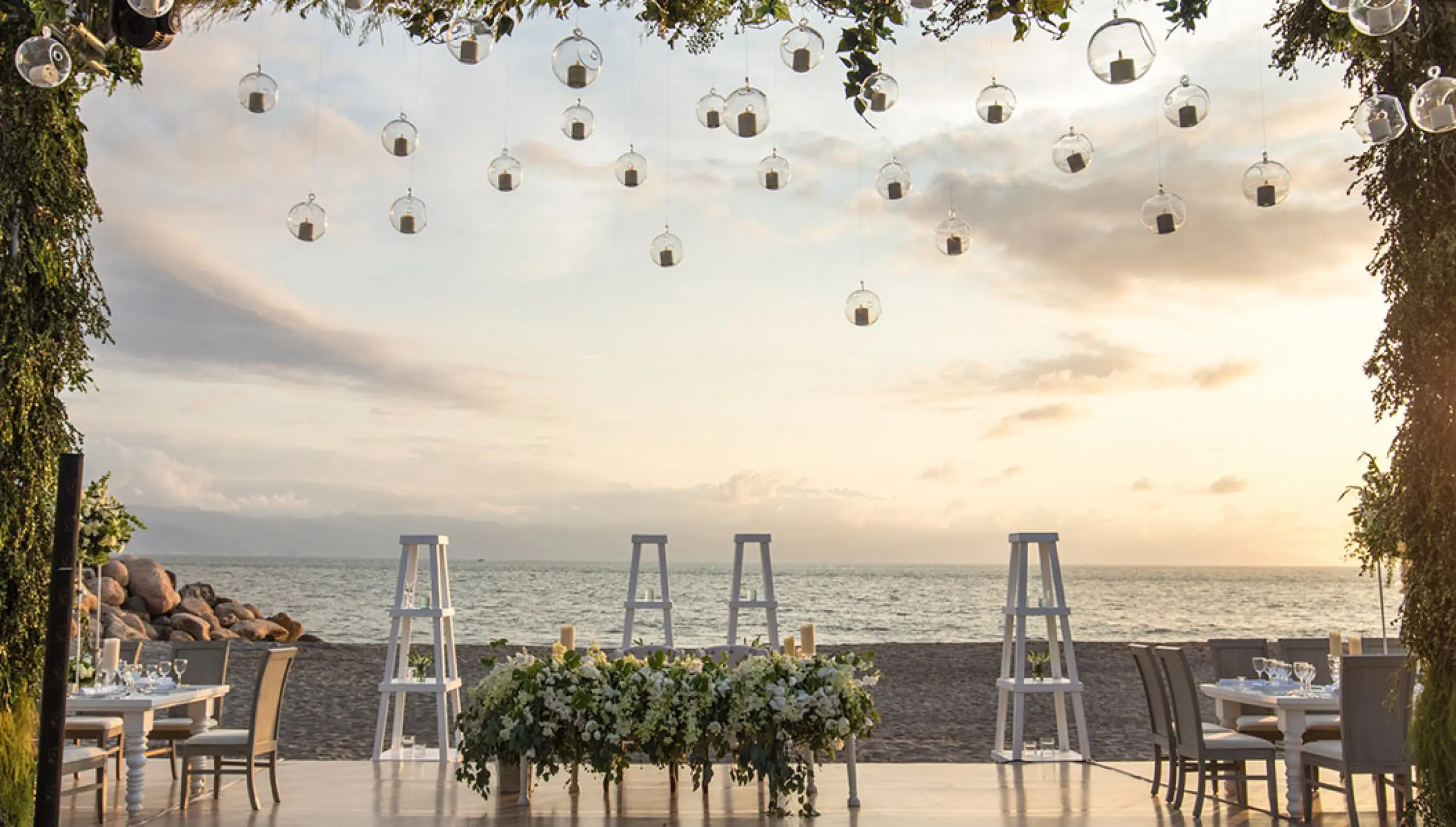 Beachfront wedding reception setup with hanging globe candles at Velas Vallarta, Puerto Vallarta