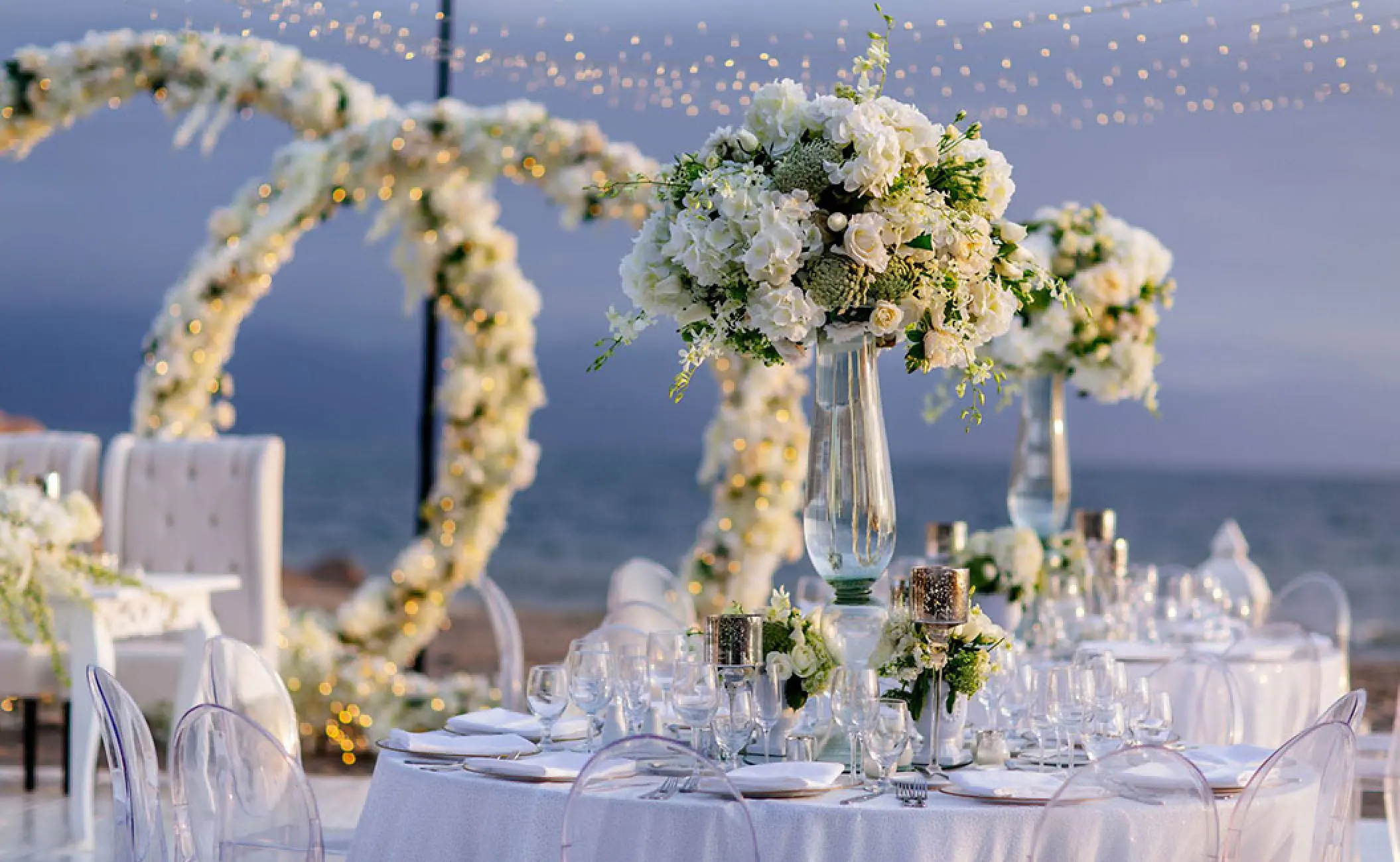 Outdoor wedding reception with white floral centerpieces and string lights at Velas Vallarta, Puerto Vallarta