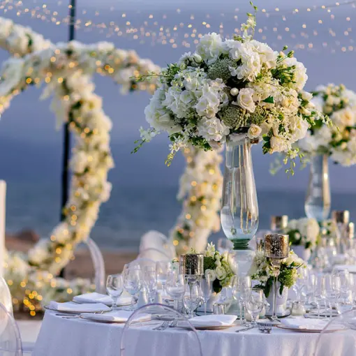 Outdoor wedding reception with white floral centerpieces and string lights at Velas Vallarta, Puerto Vallarta