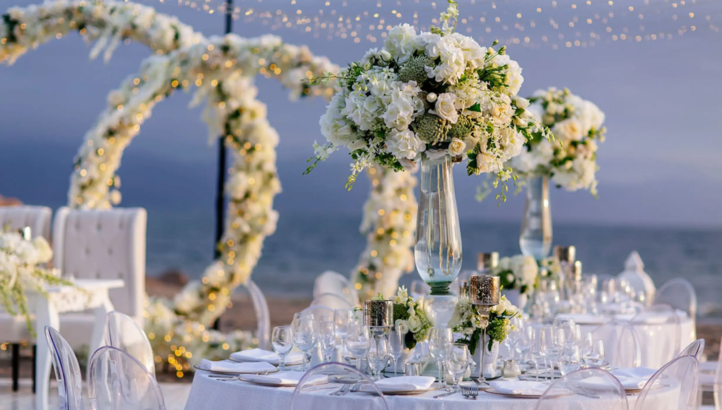 Outdoor wedding reception with white floral centerpieces and string lights at Velas Vallarta, Puerto Vallarta