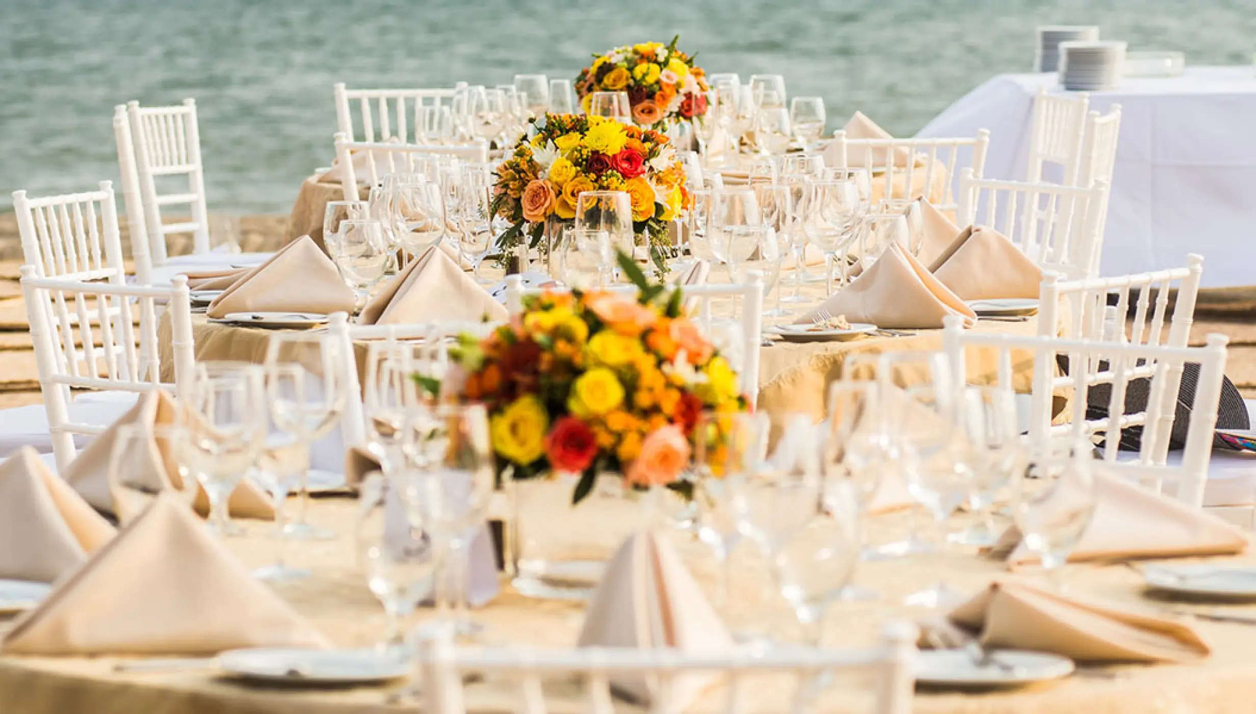 Beachfront wedding reception tables with yellow flower centerpieces at Velas Vallarta, Puerto Vallarta