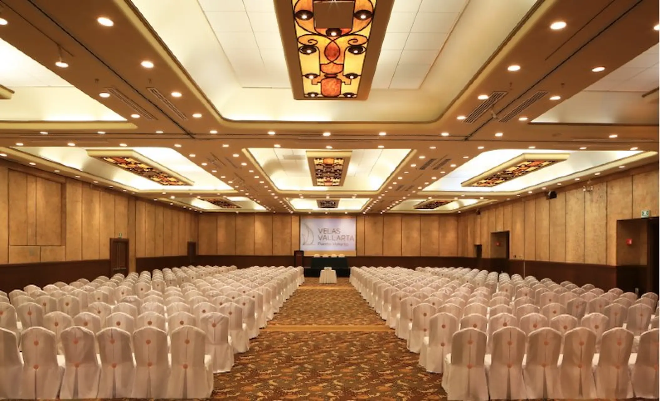 Indoor ballroom wedding ceremony setup with white chairs at Velas Vallarta, Puerto Vallarta