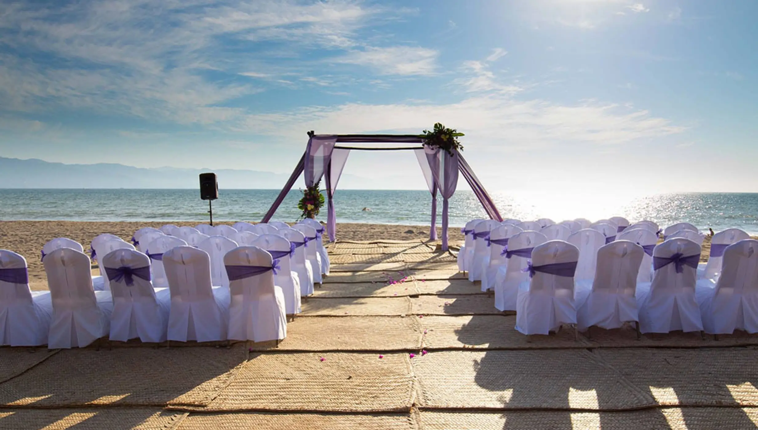 Beach wedding ceremony with purple drapery and white chairs at Velas Vallarta, Puerto Vallarta