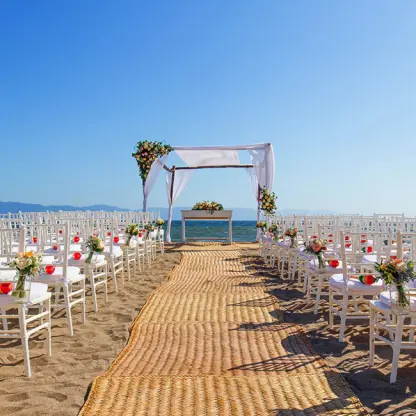 Beachfront wedding ceremony with white chairs and floral arch at Velas Vallarta, Puerto Vallarta
