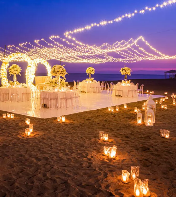 Outdoor wedding reception at Velas Vallarta, Puerto Vallarta with string lights and lanterns on the beach at dusk