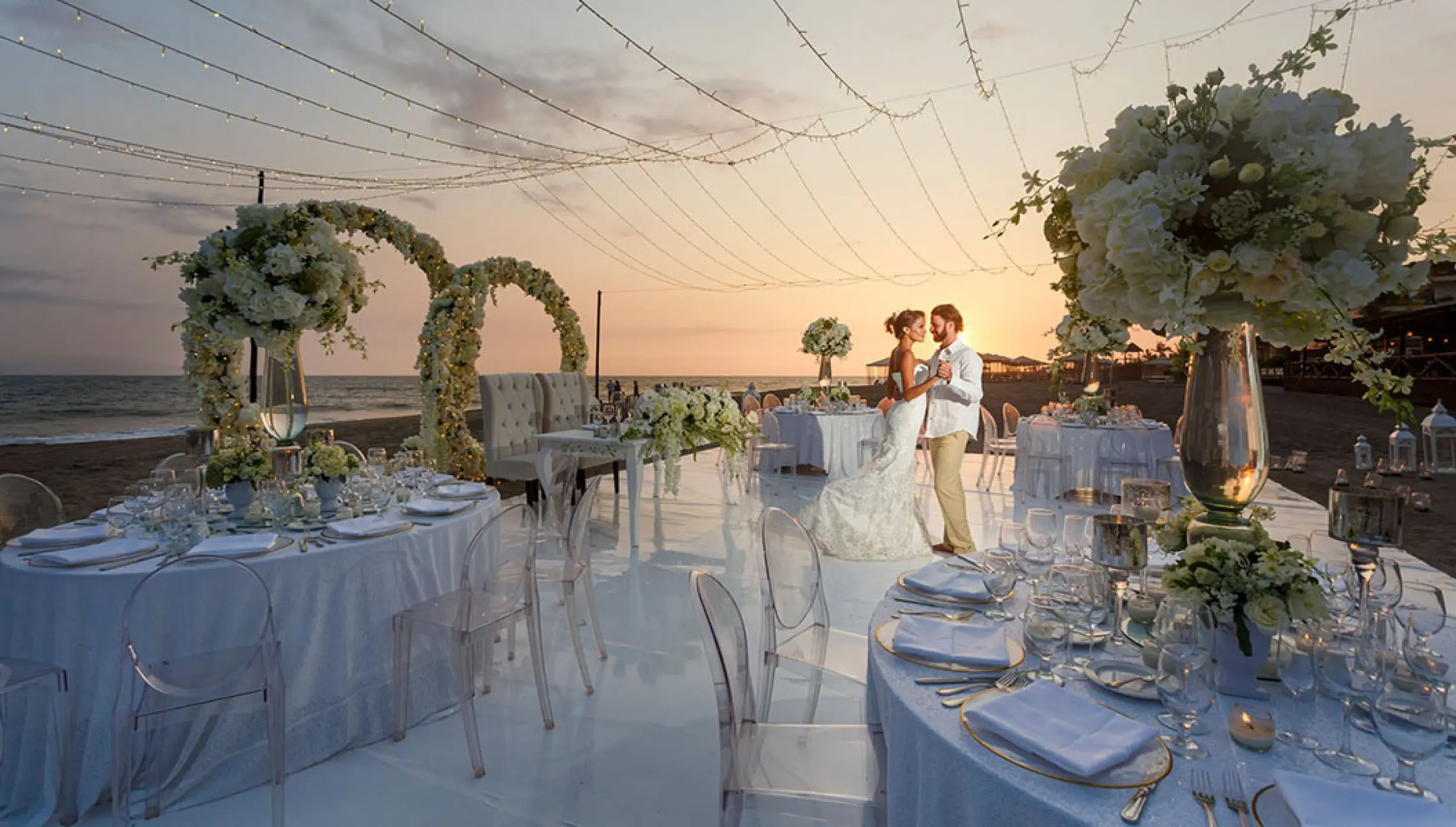 Beach reception with white floral decor and fairy lights at Velas Vallarta, Puerto Vallarta
