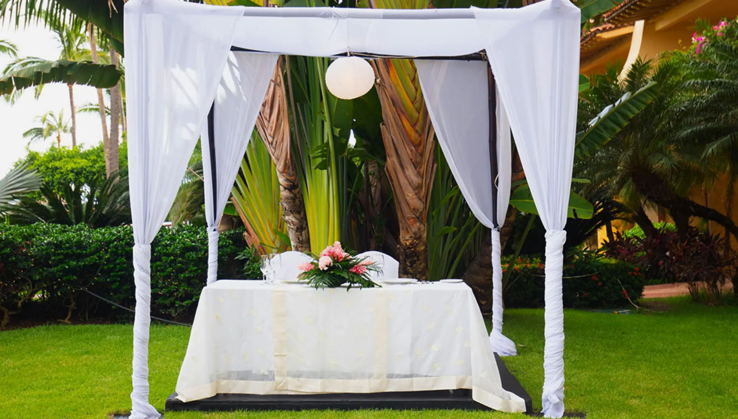 Garden wedding ceremony altar with white fabric and floral centerpiece at Velas Vallarta, Puerto Vallarta