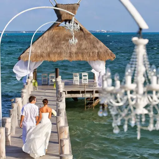 Bride and groom walking down the pier to a palapa ceremony venue at Villa del Palmar Cancun