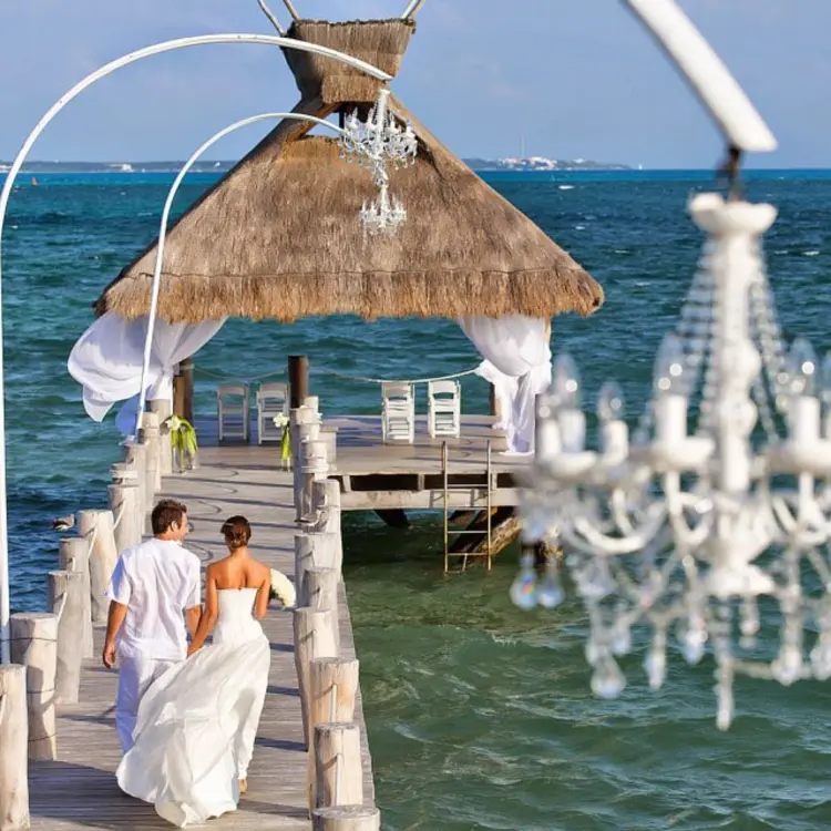 Bride and groom walking down the pier to a palapa ceremony venue at Villa del Palmar Cancun