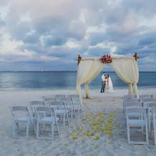 Beachfront wedding ceremony with a white fabric arch and the couple at Villa del Palmar, Cancun