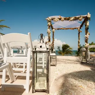 Beachfront wedding ceremony setup with white chairs and a floral arch at Villa del Palmar, Cancun