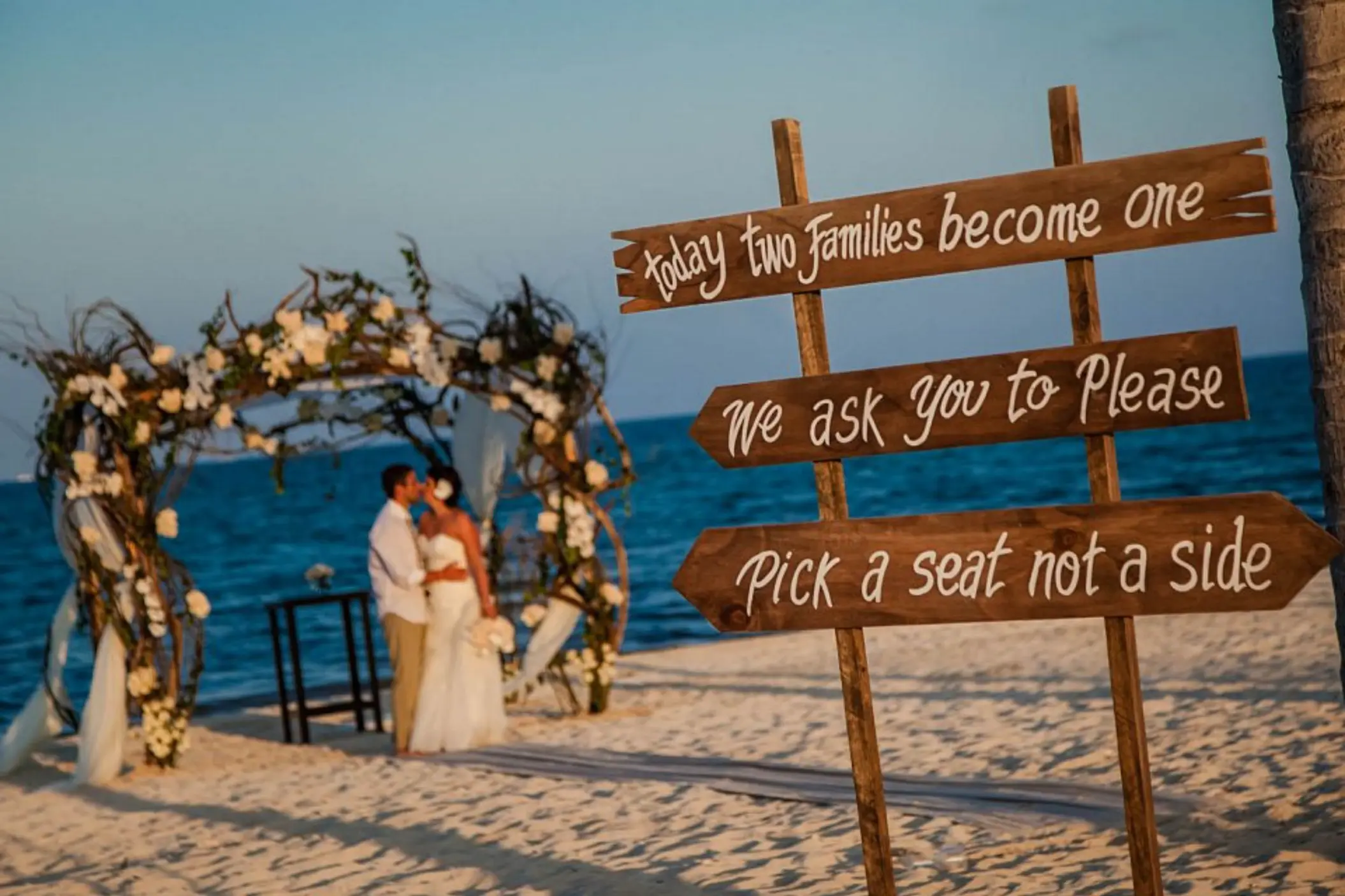 Wooden wedding sign on the beach with the bride and groom at Villa del Palmar, Cancun