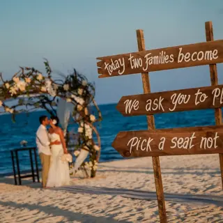 Wooden wedding sign on the beach with the bride and groom at Villa del Palmar, Cancun