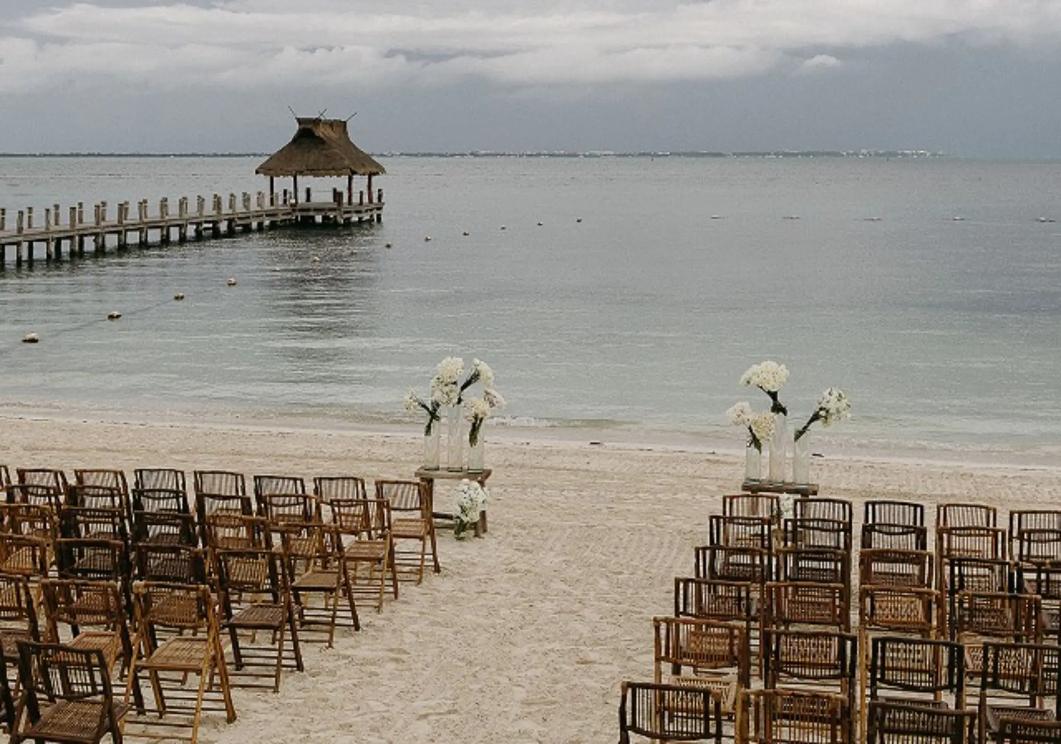 Beachfront wedding ceremony at Villa del Palmar Cancun with a long wooden pier in the background