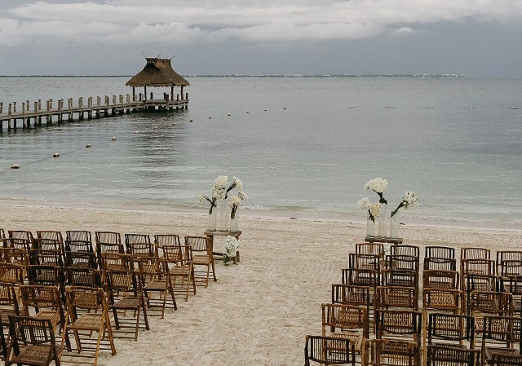 Beachfront wedding ceremony at Villa del Palmar Cancun with a long wooden pier in the background