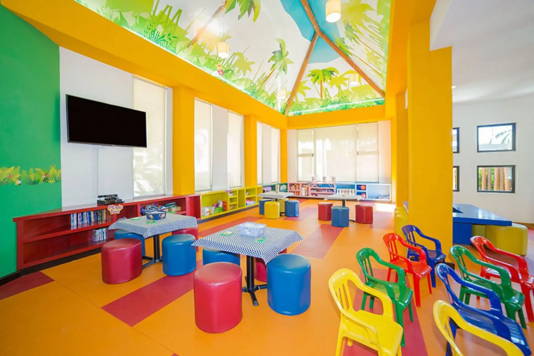 Colorful kids club with muraled ceiling and bright plastic seating at Villa del Palmar Cancun