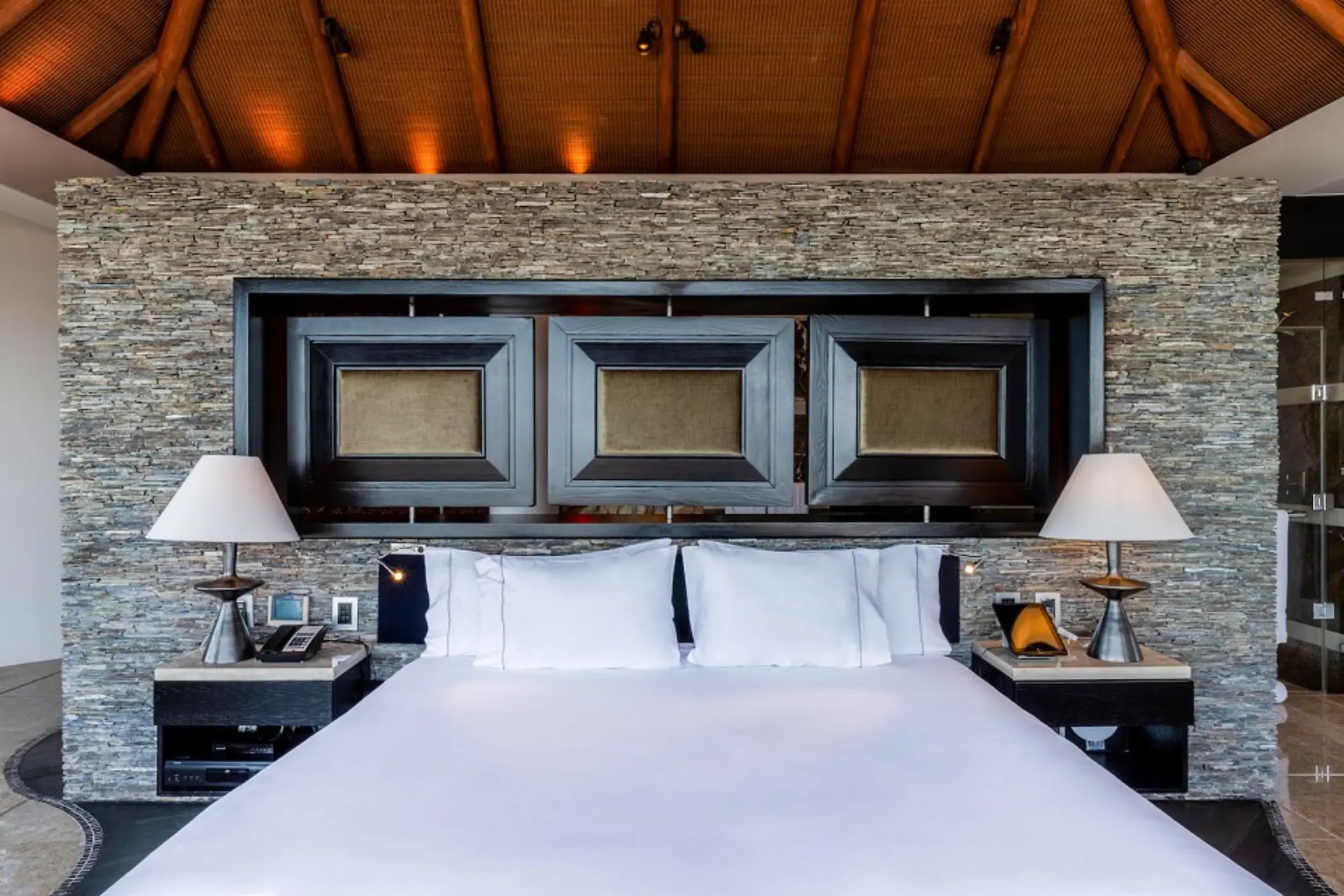 Grand Penthouse king bed with stone feature wall and palapa-style ceiling at Villa del Palmar, Cancun