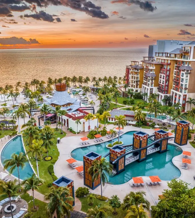 Aerial view of Villa del Palmar Cancun swimming pools and beachfront at sunset, Cancun