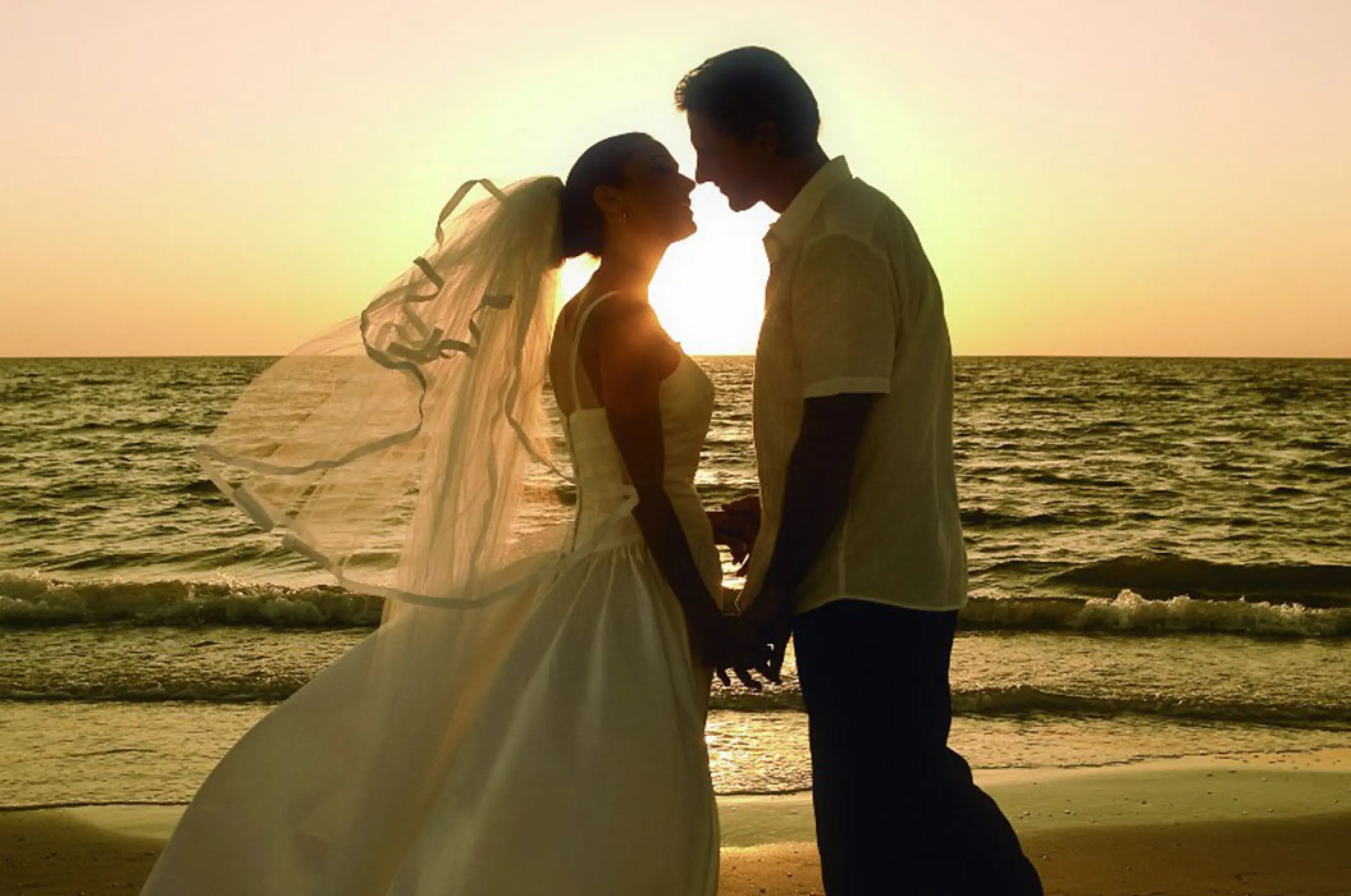 Silhouette of a couple holding hands during a sunset beach wedding at Villa La Estancia Riviera Nayarit