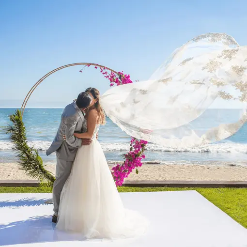 The bride and groom kissing in front of a circular floral arch at Villa La Estancia Riviera Nayarit, Puerto Vallarta