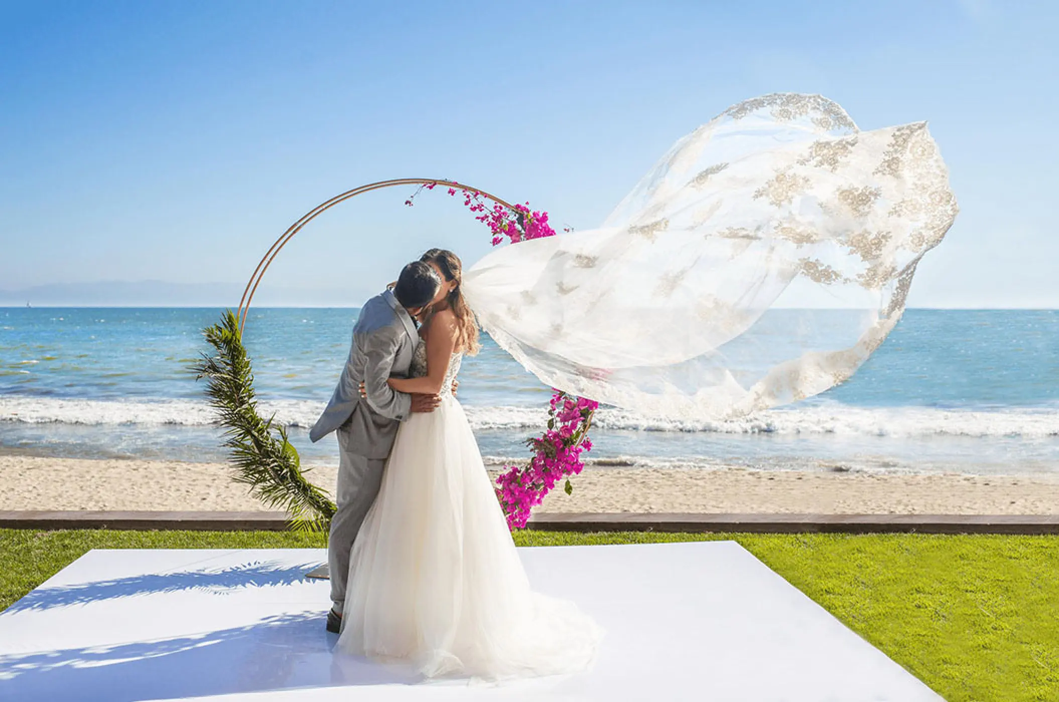 The bride and groom kissing in front of a circular floral arch at Villa La Estancia Riviera Nayarit, Puerto Vallarta