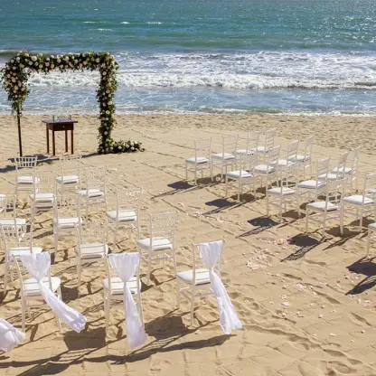 Beachfront wedding ceremony with white chairs and floral arch at Villa La Estancia, Puerto Vallarta