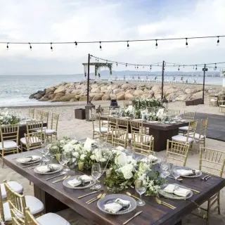 Beachfront wedding reception at Villa Premiere, Puerto Vallarta with wooden tables, gold chairs, and string lights
