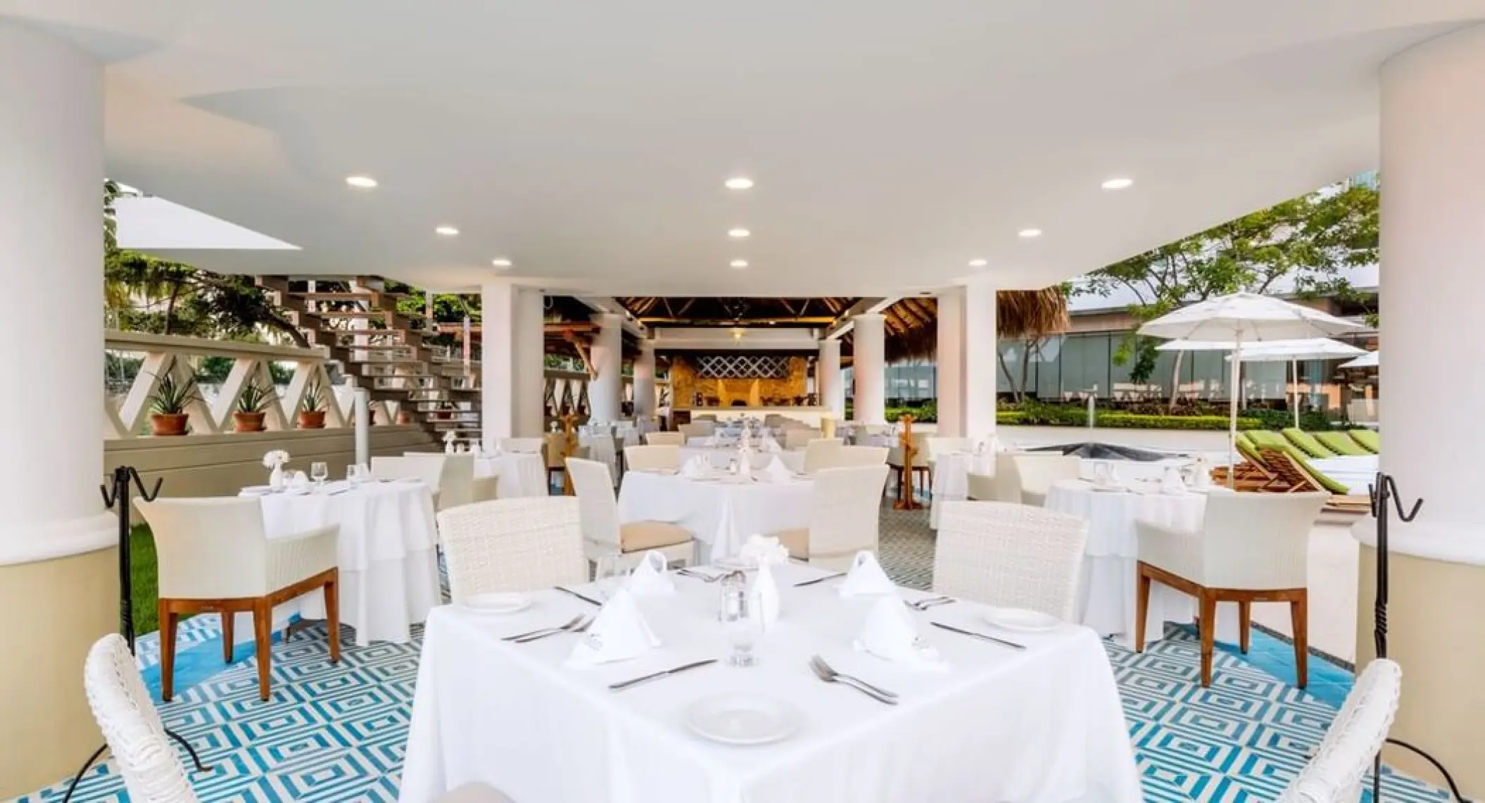 Outdoor restaurant dining area with white tables and chairs at Villa Premiere Boutique Hotel, Puerto Vallarta