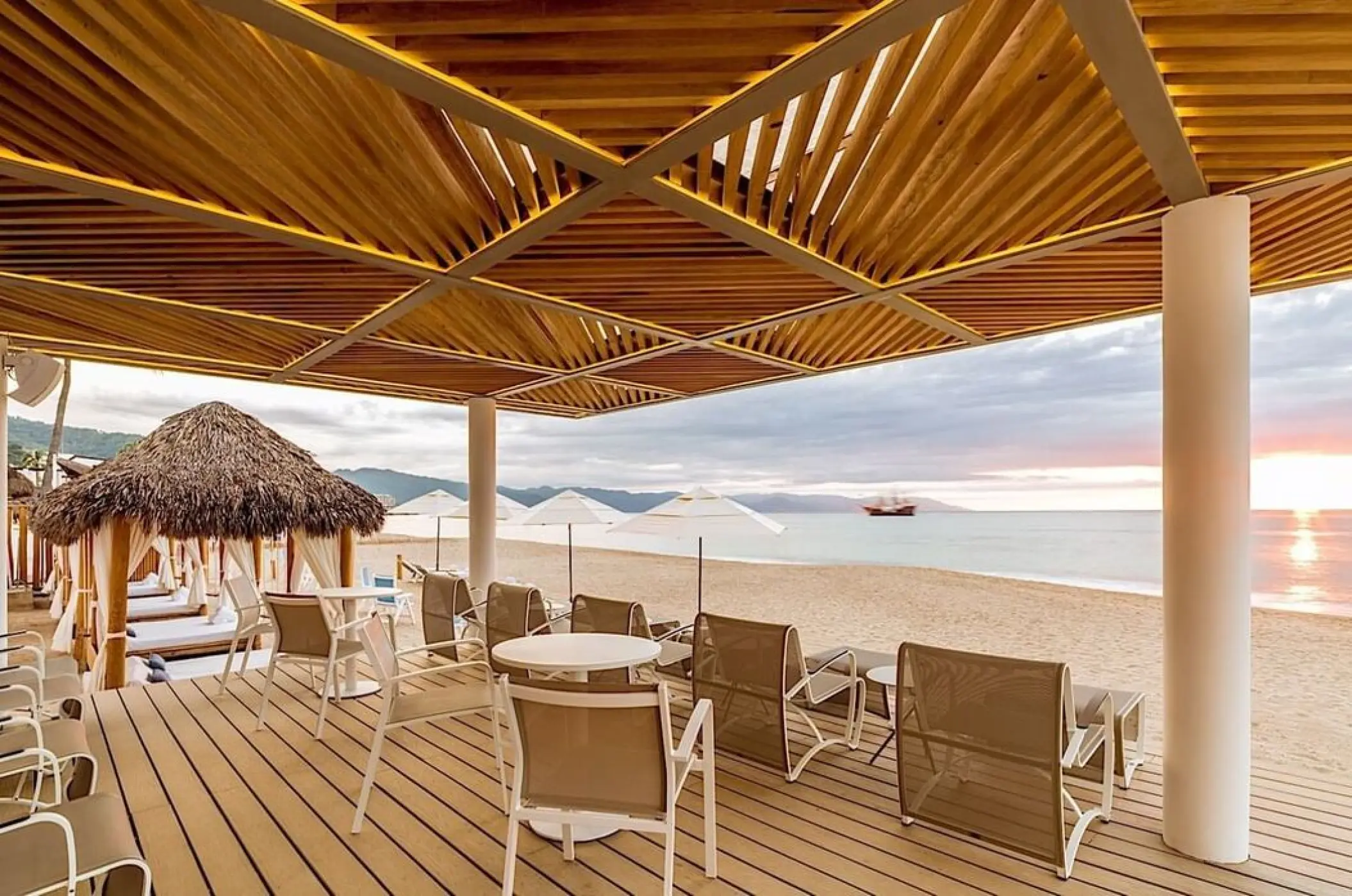 Beachfront seating and loungers under a wooden pavilion at Villa Premiere Boutique Hotel, Puerto Vallarta