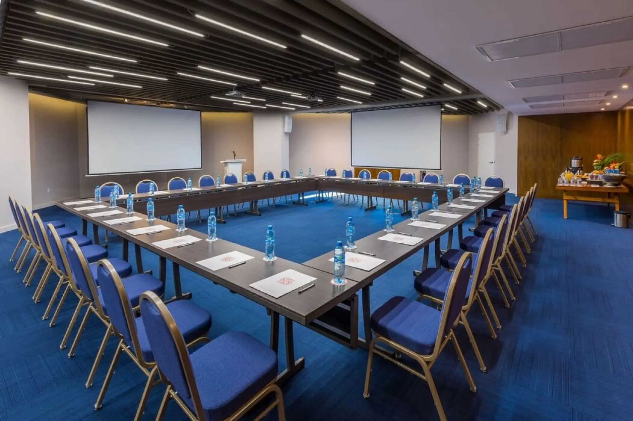 U-shaped meeting room setup with blue chairs and projection screens at Villa Premiere Boutique Hotel, Puerto Vallarta