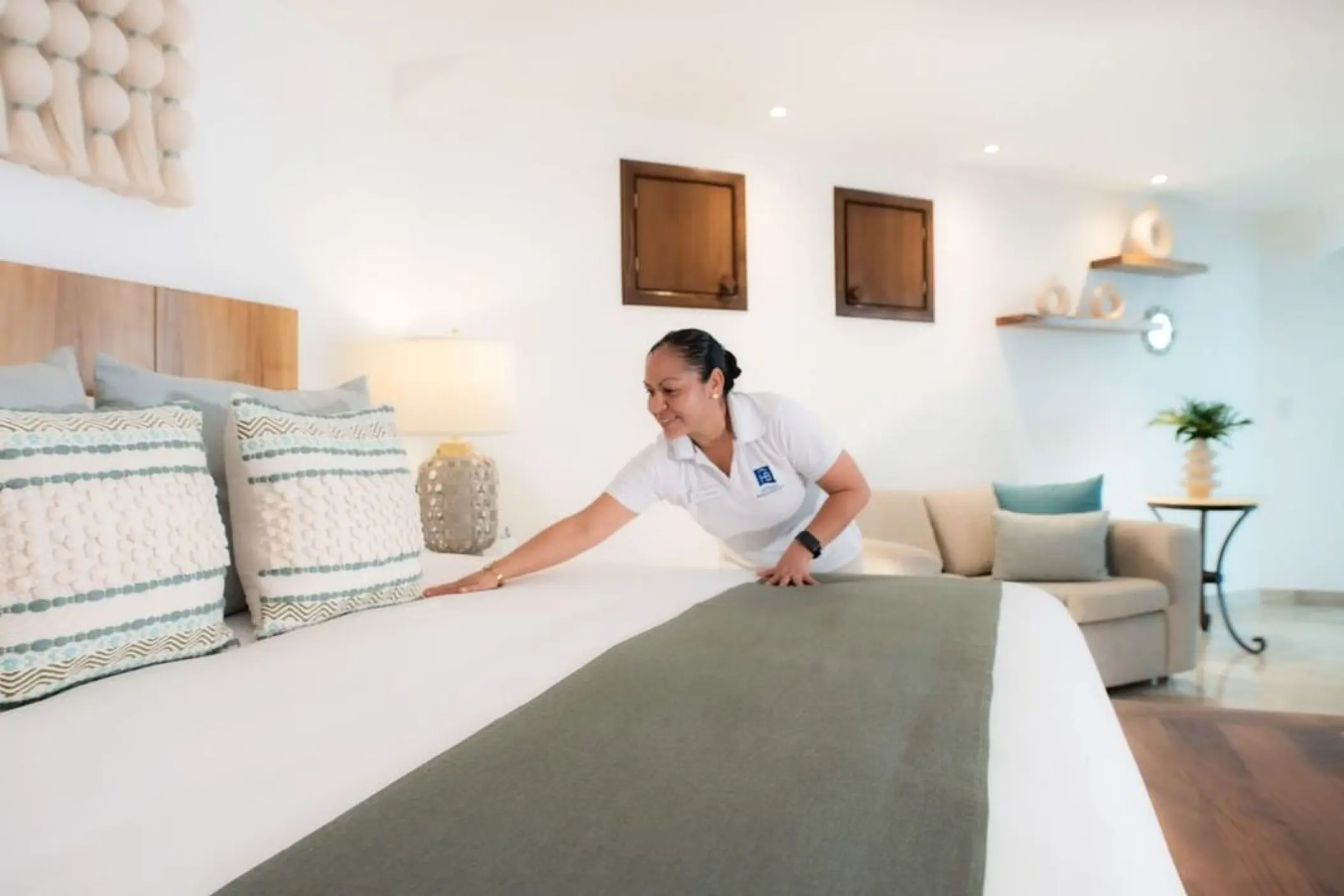Paradise Weddings staff member straightening bedding in a guest suite at Villa Premiere Boutique Hotel, Puerto Vallarta