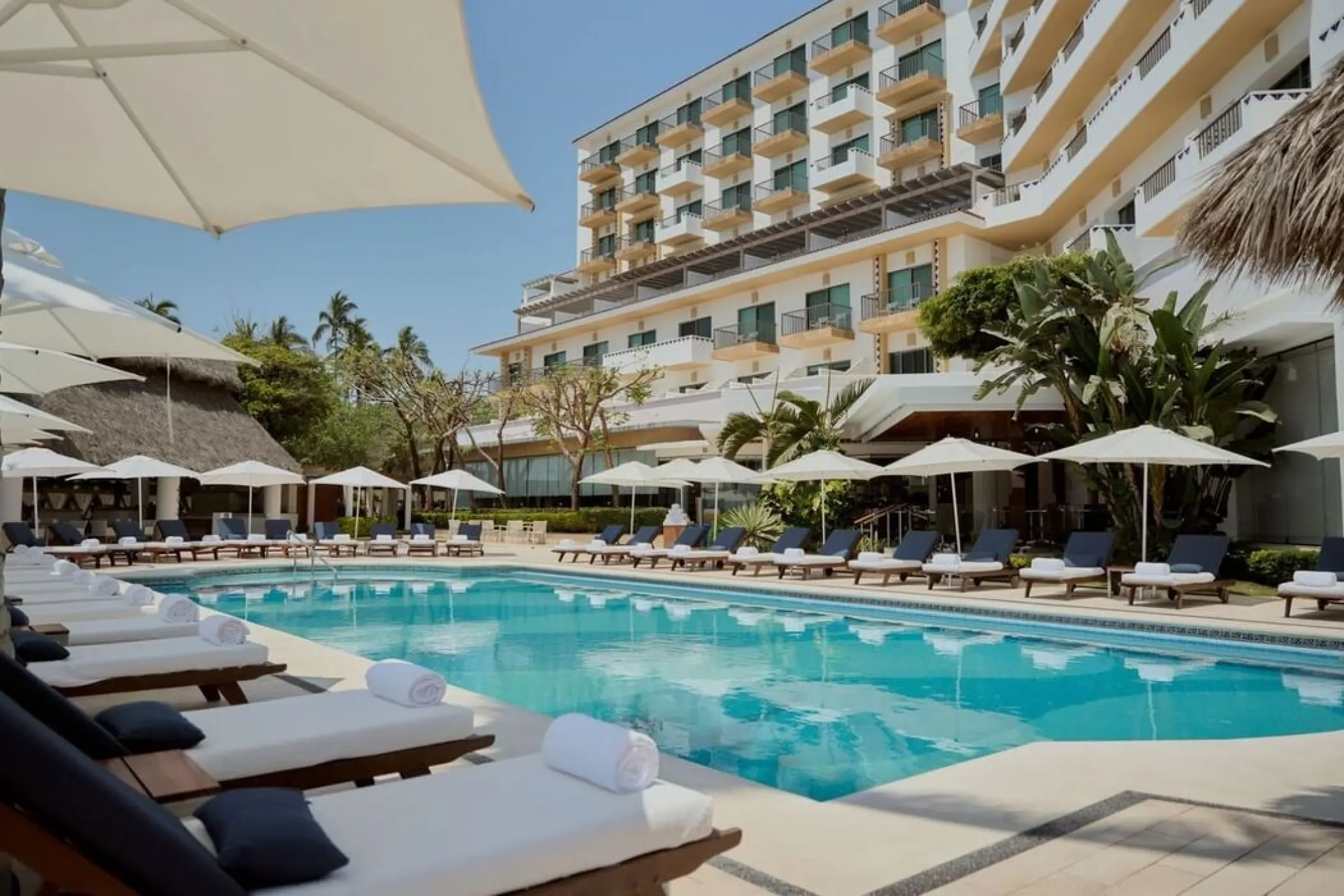 Villa Premiere Boutique pool surrounded by lounge chairs and white umbrellas in Puerto Vallarta
