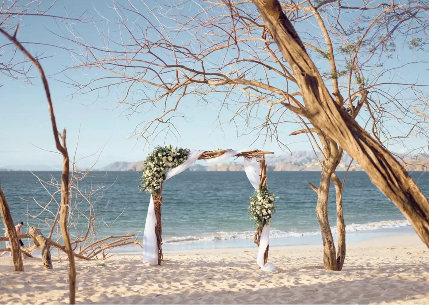 Beachfront wedding ceremony arch framed by trees at Westin Reserva Conchal, Liberia